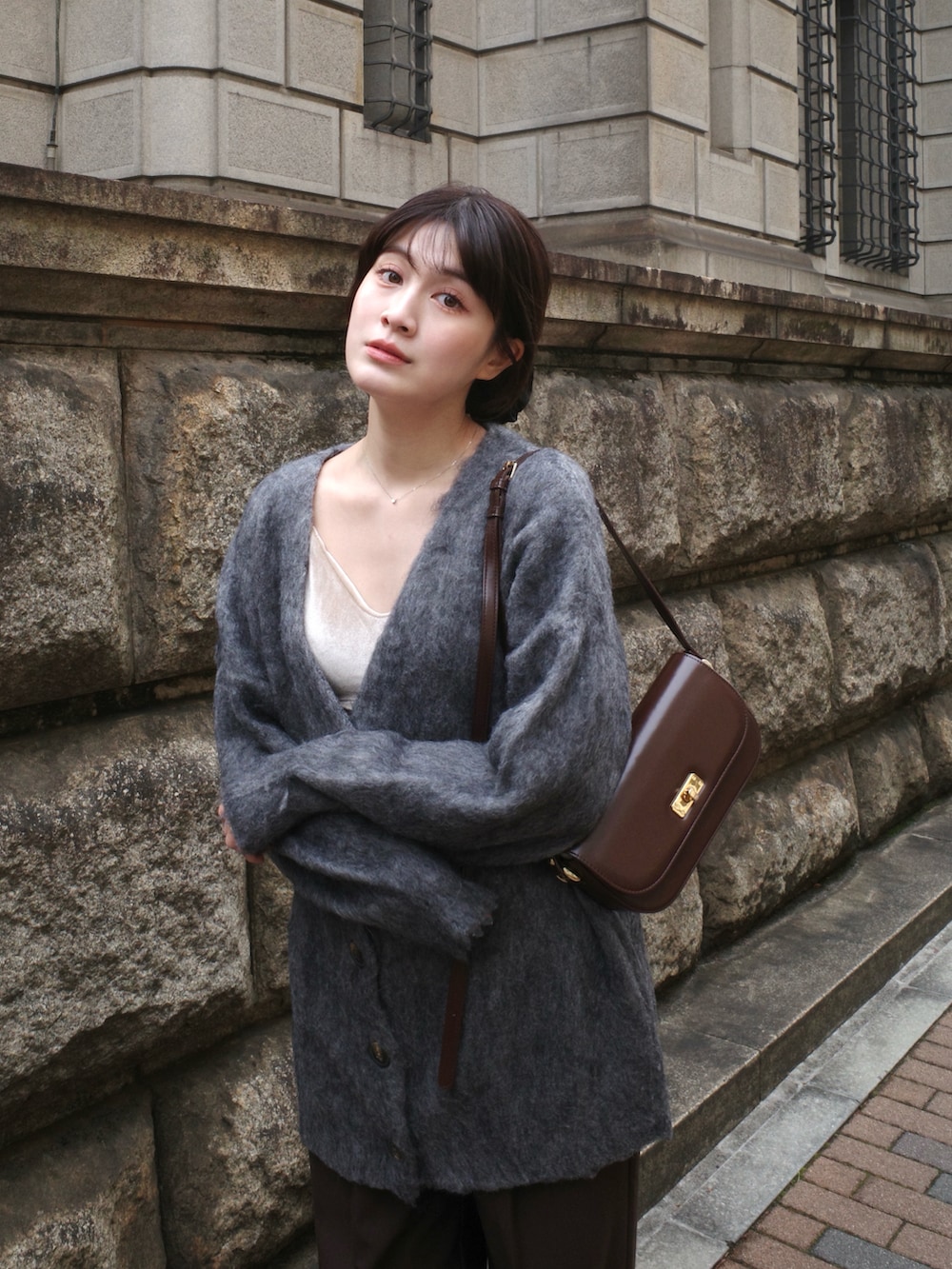 グレー系のカーディガン/ボレロ、ホワイト系のキャミソール、ブラウン系のパンツを着用したレディースの冬コーディネートの3枚目の写真