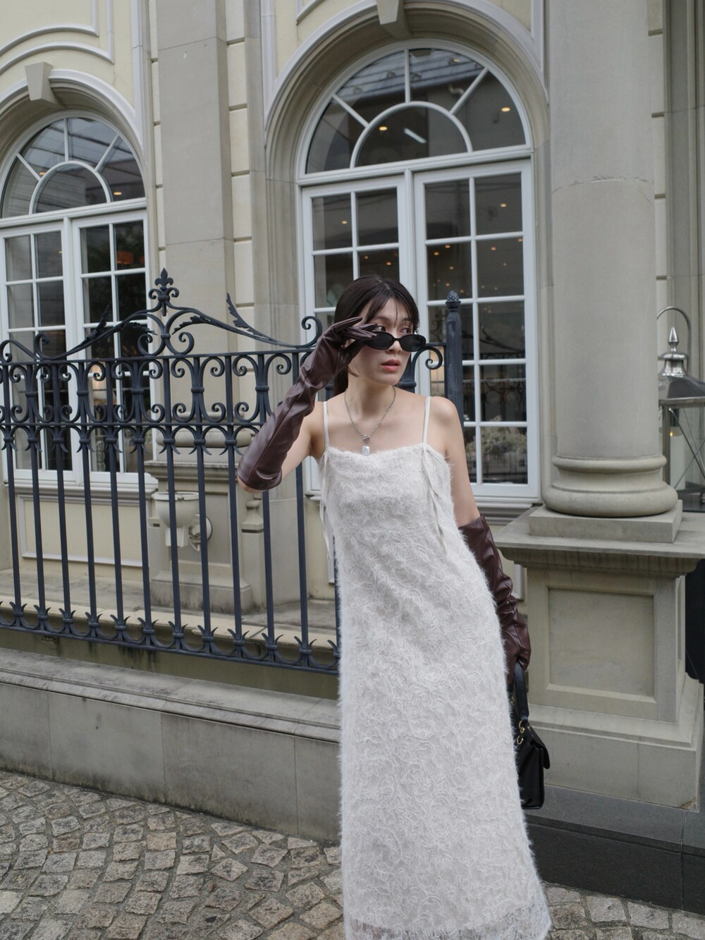 ゴールド系のブーツ、ホワイト系のワンピース/ドレス、ブラック系のショルダーバッグを着用したレディースの秋コーディネートの2枚目の写真