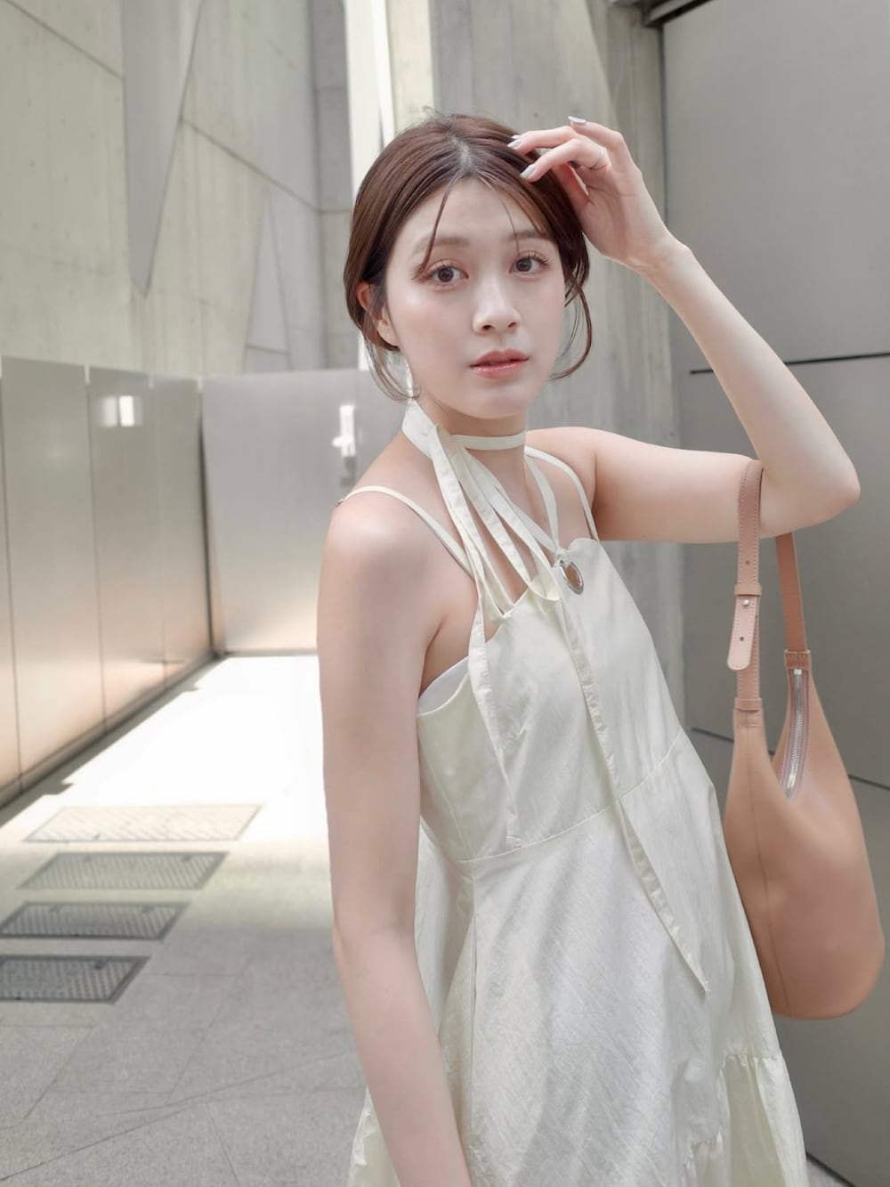 ホワイト系のワンピース、ブラウン系のバッグ、ゴールド系のパンプスを着用したレディースの夏コーディネートの2枚目の写真