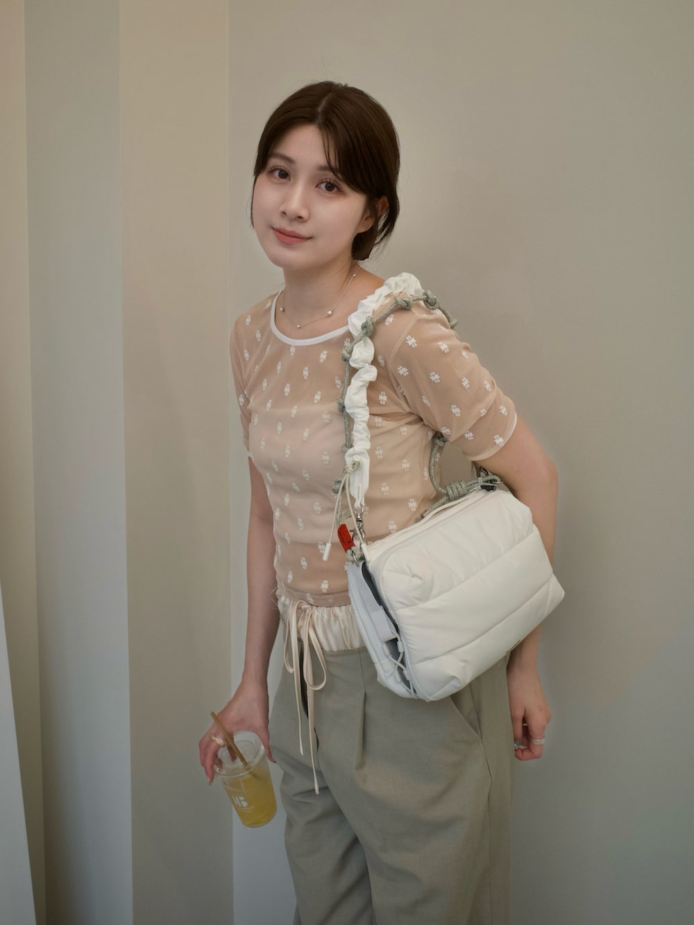 ベージュ系のTシャツ/カットソー、ベージュ系のパンツ、ホワイト系のショルダーバッグを着用したレディースの春コーディネートの2枚目の写真