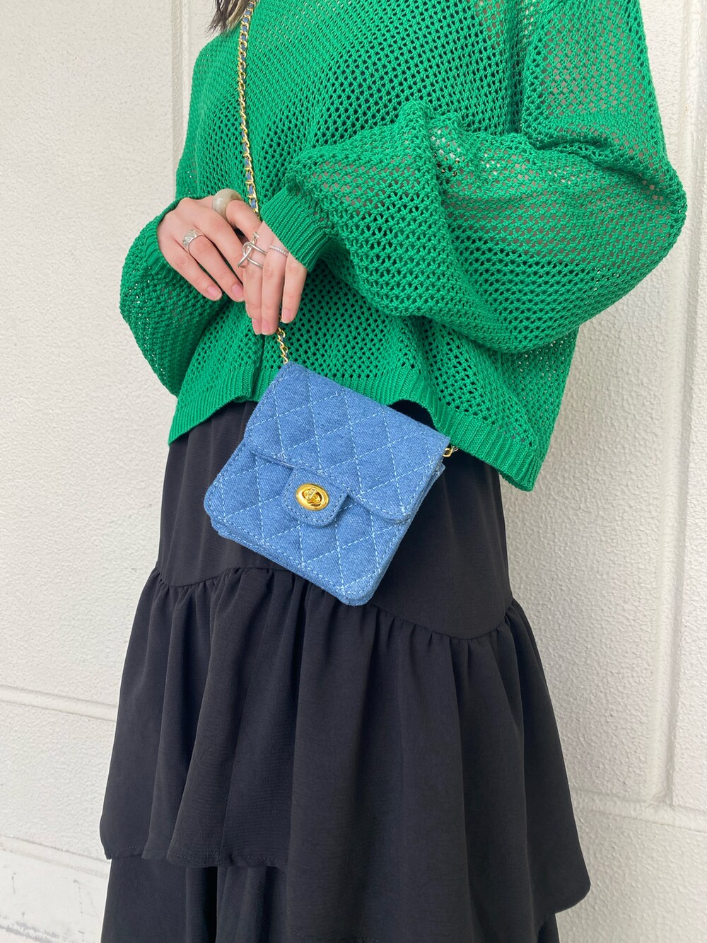 ブラック系のスカート、グリーン系のニット/セーター、ブルー系のバッグを着用したレディースの春コーディネートの3枚目の写真