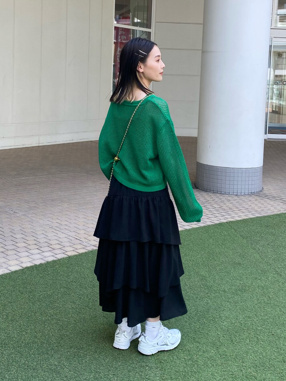 ブラック系のスカート、グリーン系のニット/セーター、ブルー系のバッグを着用したレディースの春コーディネートの2枚目の写真