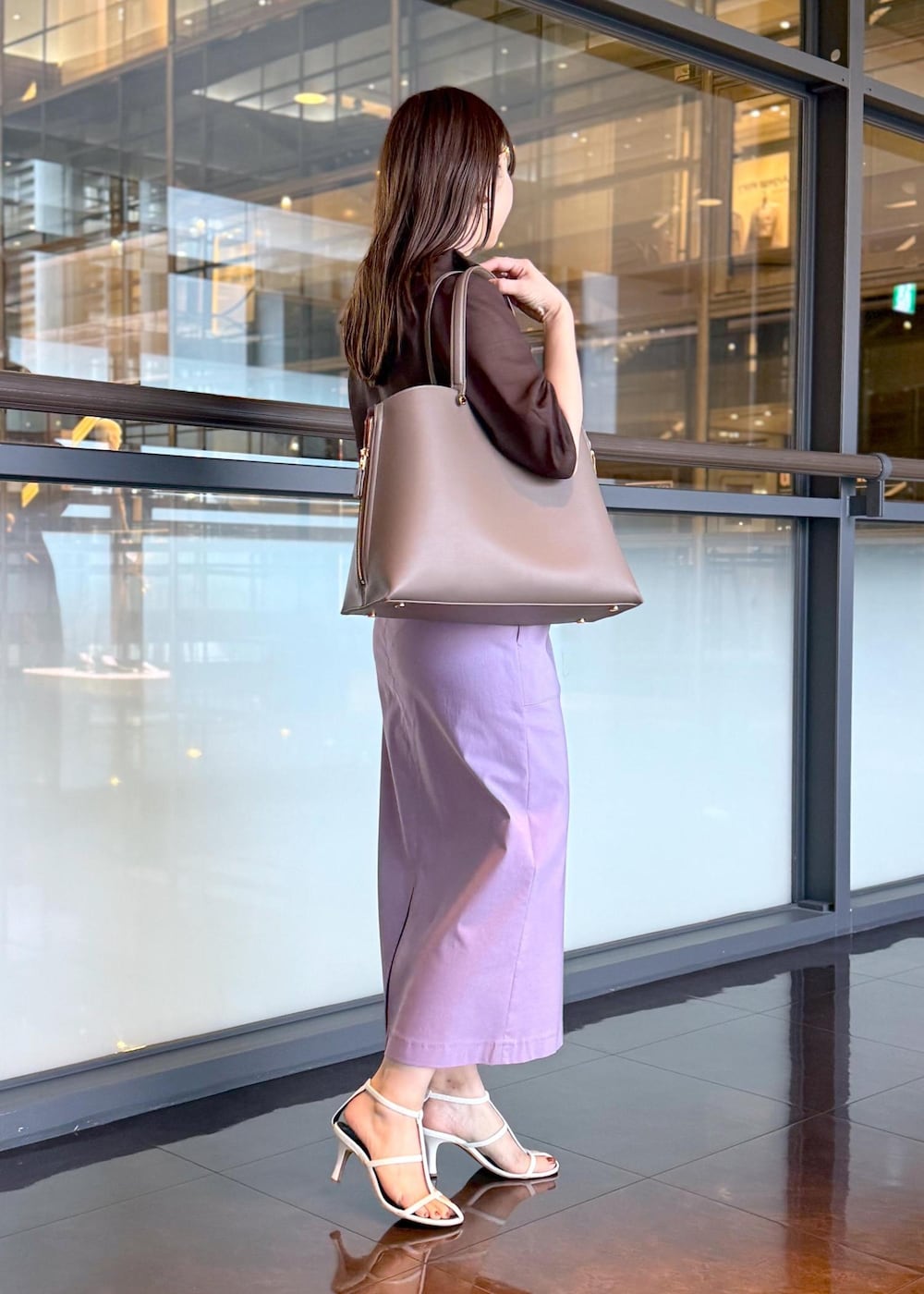 ブラウン系のトートバッグ、パープル系のスカート、ブラウン系のシャツ/ブラウスを着用したレディースの春コーディネートの2枚目の写真