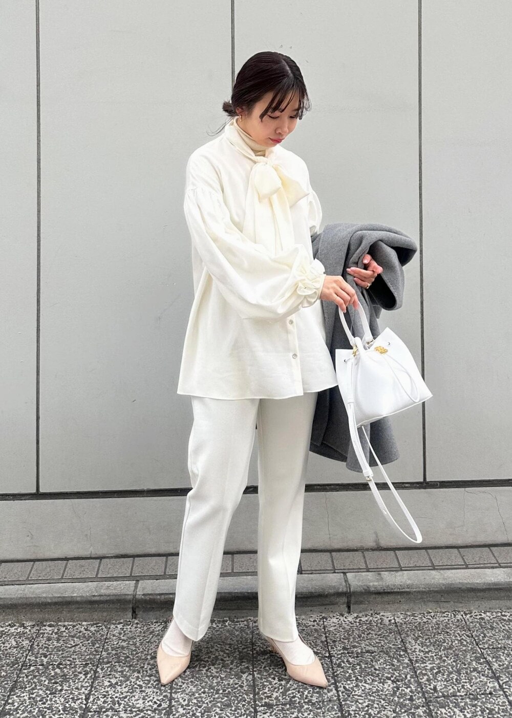 グレー系のその他アウター、ベージュ系のパンプス、ホワイト系のハンドバッグを着用したレディースの冬コーディネートの2枚目の写真