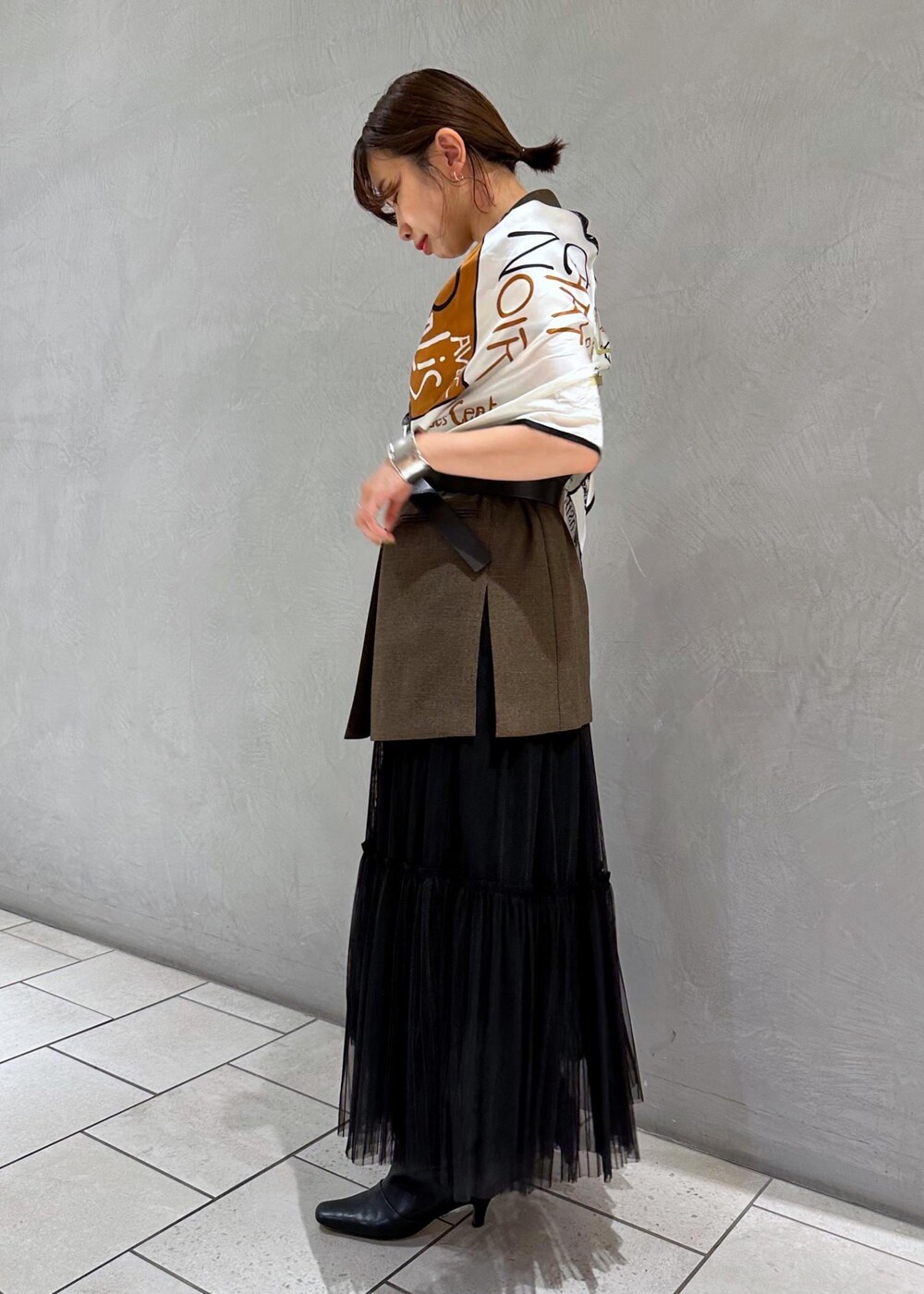 ブラック系のスカート、ゴールド系のブローチ/コサージュ、ブラック系のバンダナ/スカーフを着用したレディースの夏コーディネートの2枚目の写真