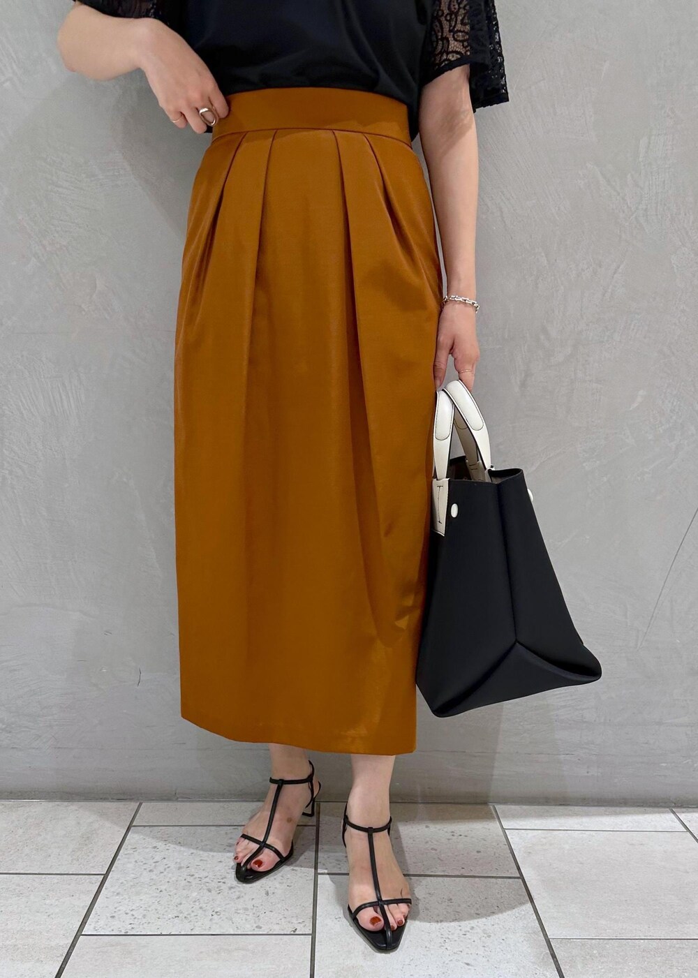 ブラック系のハンドバッグ、ブラック系のサンダル、ブラック系のTシャツ/カットソーを着用したレディースの夏コーディネートの5枚目の写真