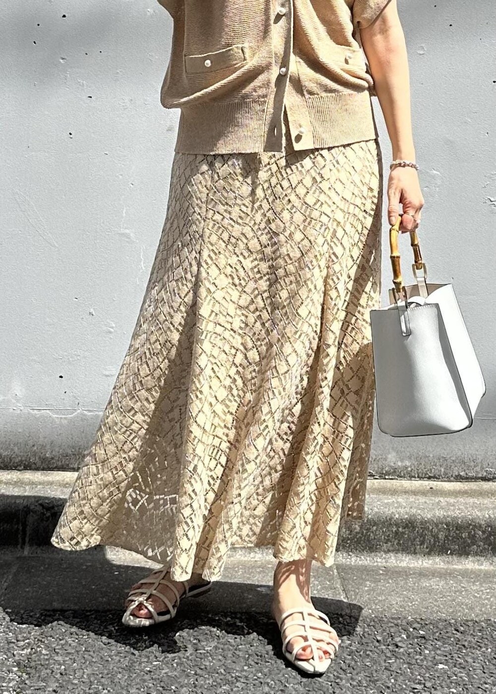 ベージュ系のスカート、ホワイト系のハンドバッグ、ホワイト系のサンダルを着用したレディースの春コーディネートの7枚目の写真