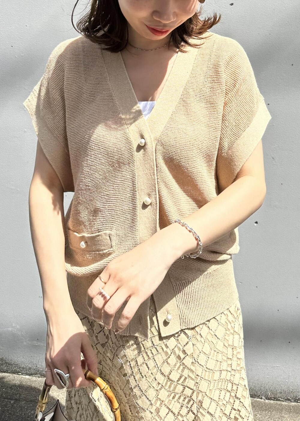 ベージュ系のスカート、ホワイト系のハンドバッグ、ホワイト系のサンダルを着用したレディースの春コーディネートの4枚目の写真