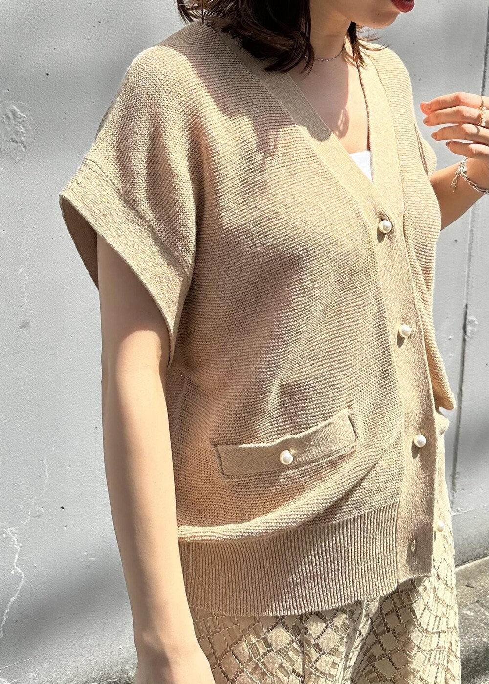 ベージュ系のスカート、ホワイト系のハンドバッグ、ホワイト系のサンダルを着用したレディースの春コーディネートの5枚目の写真