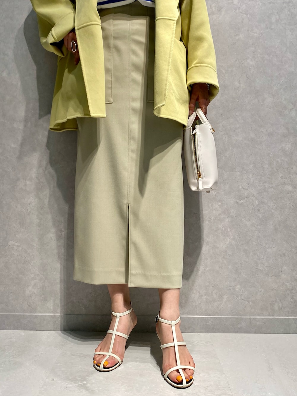 ブルー系のTシャツ/カットソー、イエロー系のトレンチコート、ベージュ系のスカートを着用したレディースの春コーディネートの5枚目の写真