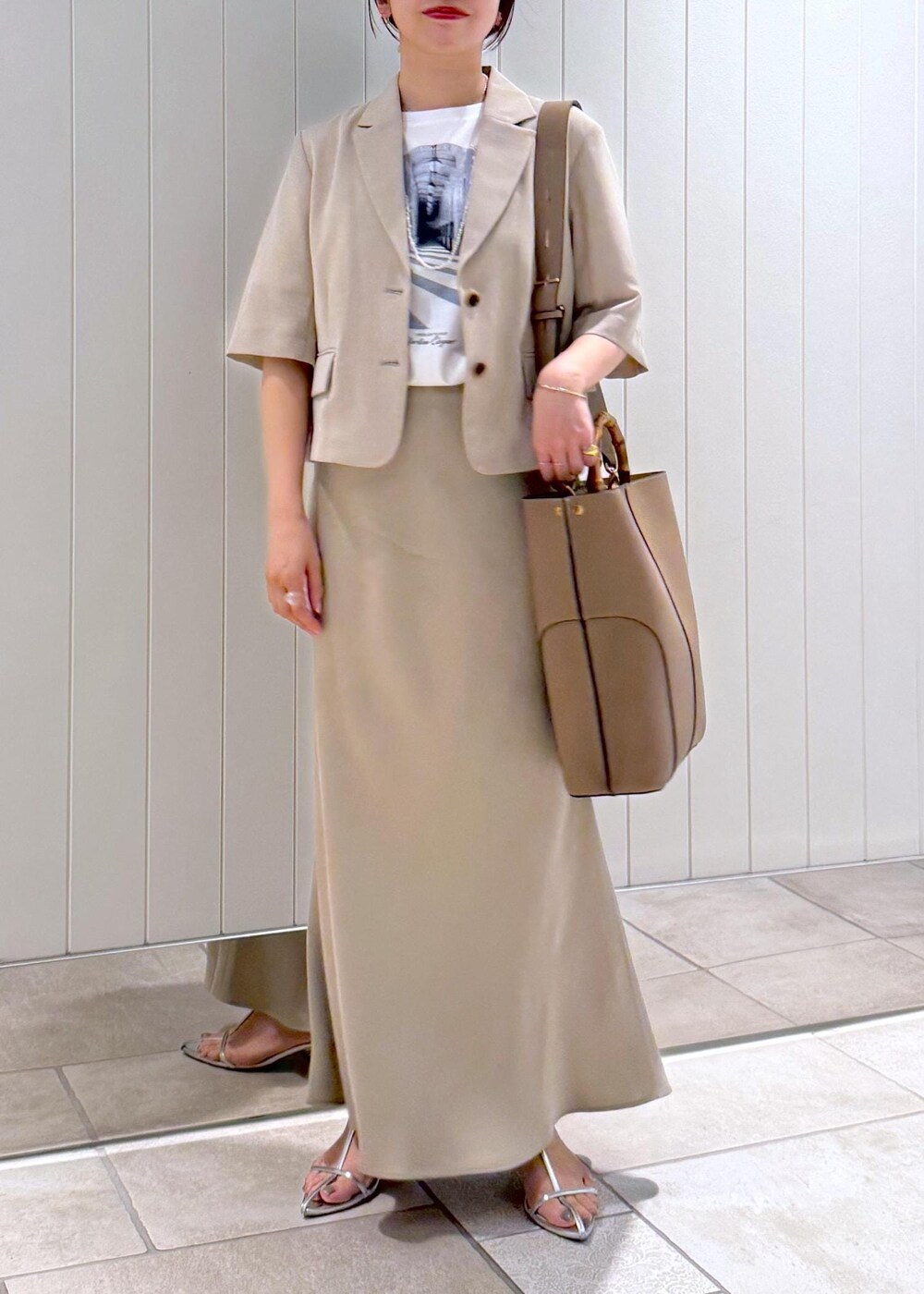 ベージュ系のトートバッグ、ホワイト系のTシャツ/カットソー、ベージュ系のスカートを着用したレディースの春コーディネートの4枚目の写真
