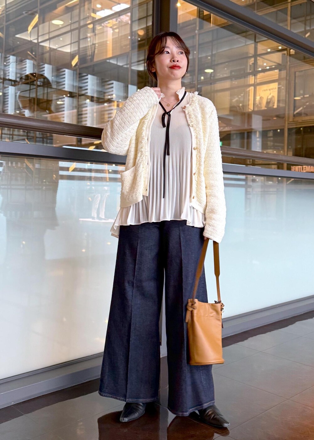 ブルー系のデニムパンツ、イエロー系のハンドバッグ、ホワイト系のノーカラージャケットを着用したレディースの秋コーディネートの2枚目の写真