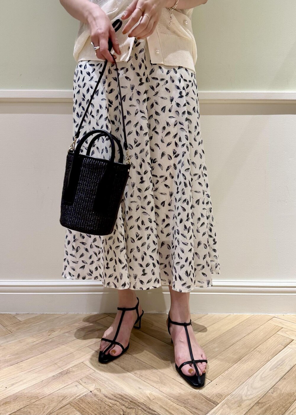 ブラック系のハンドバッグ、ホワイト系のスカート、ブラック系のサンダルを着用したレディースの夏コーディネートの7枚目の写真