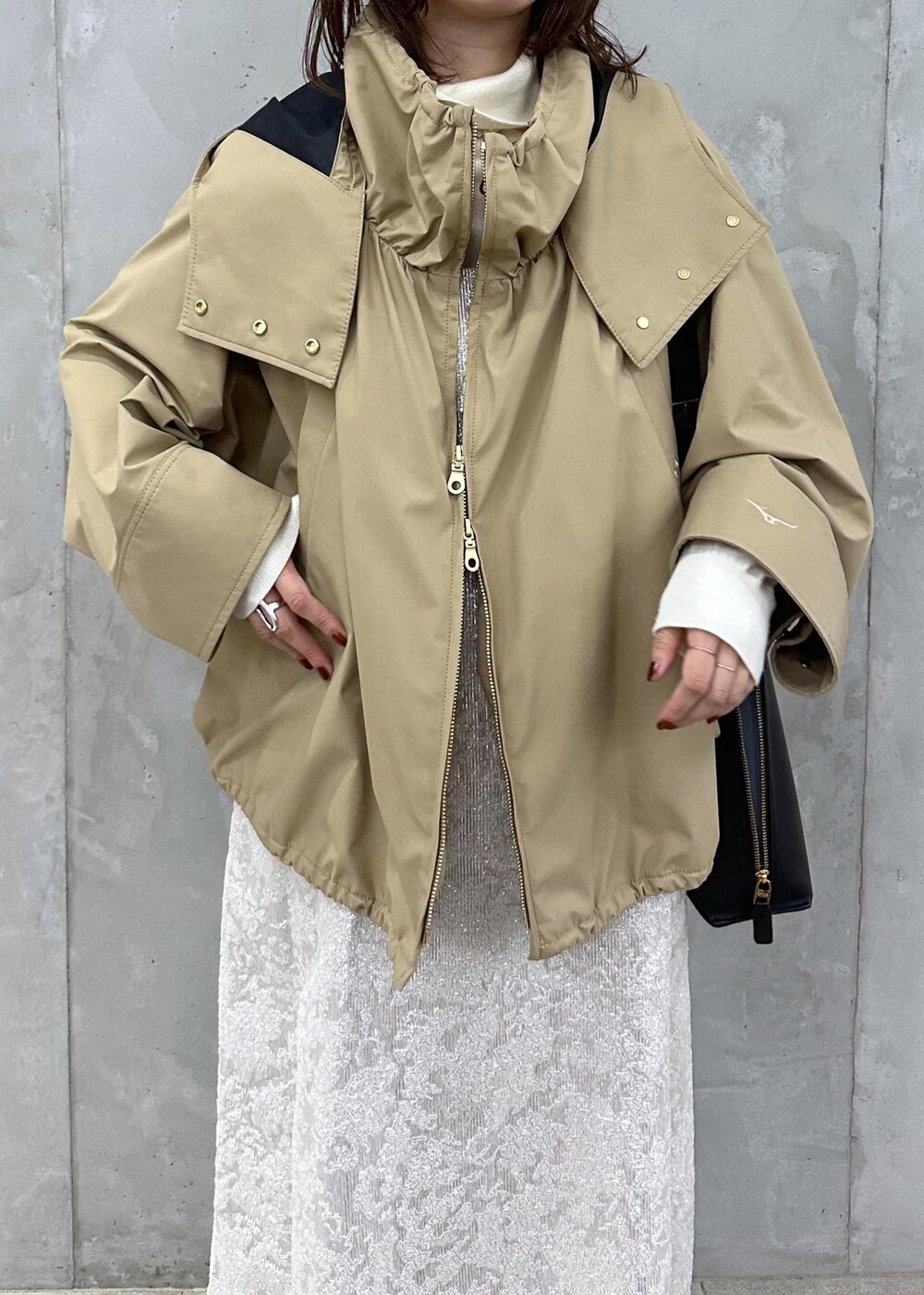 ブラック系のブーツ、ホワイト系のワンピース、ベージュ系のマウンテンパーカーを着用したレディースの秋コーディネートの5枚目の写真