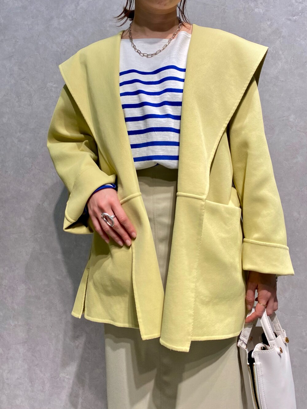 ブルー系のTシャツ/カットソー、イエロー系のトレンチコート、ベージュ系のスカートを着用したレディースの春コーディネートの3枚目の写真