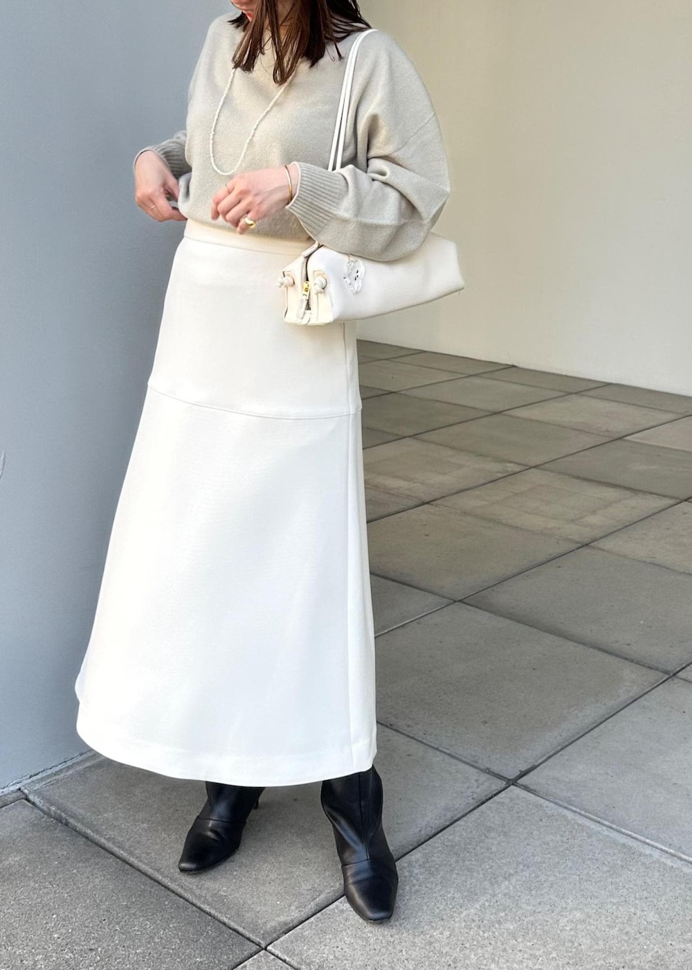 ホワイト系のハンドバッグ、ホワイト系のスカート、ベージュ系のニット/セーターを着用したレディースの冬コーディネートの6枚目の写真