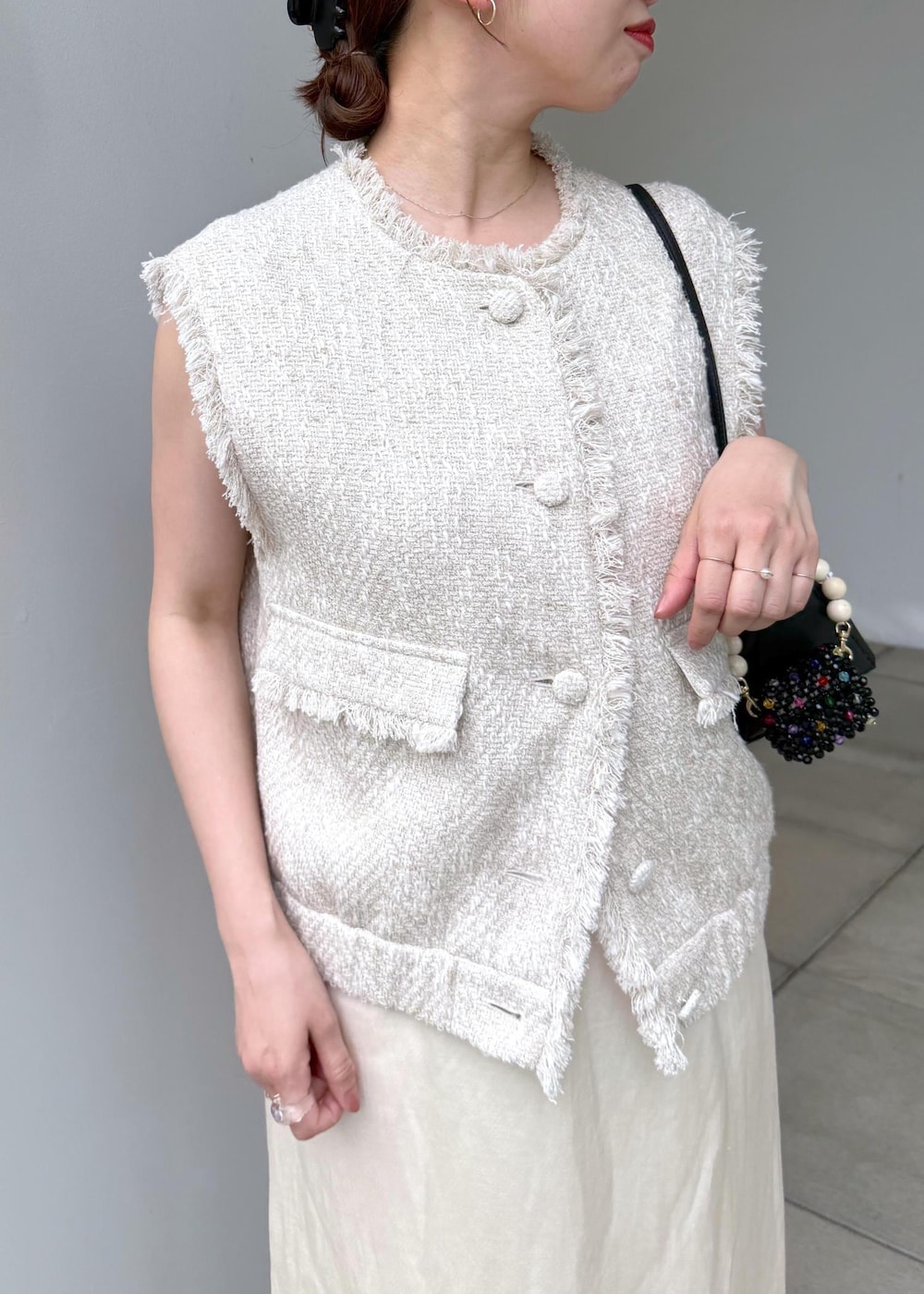 ホワイト系のスカート、ホワイト系のベストを着用したレディースの夏コーディネートの5枚目の写真