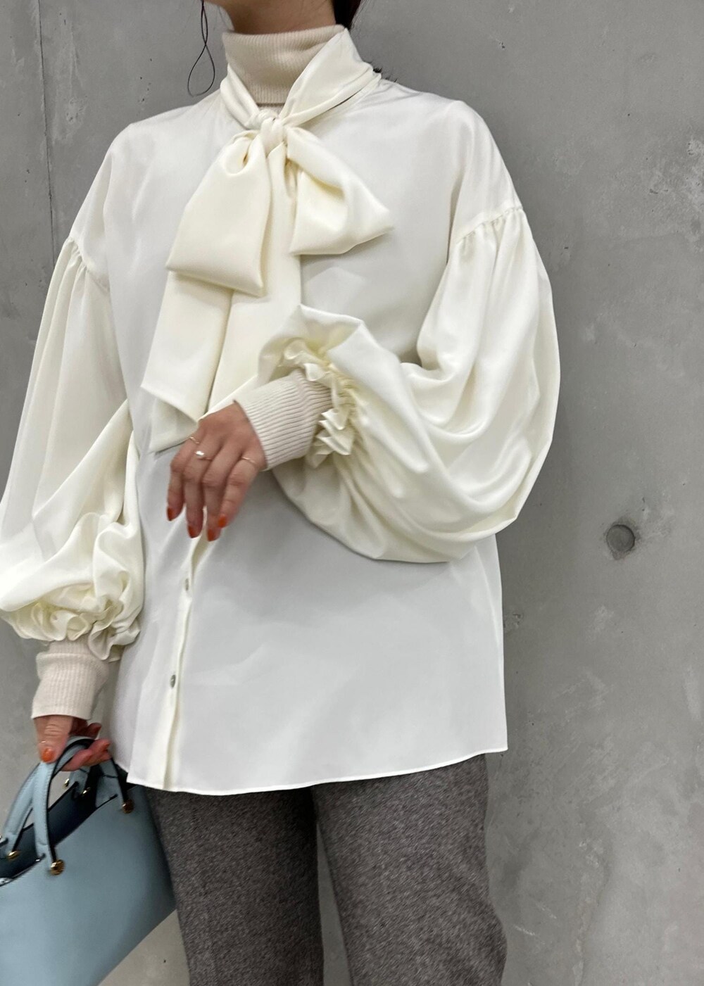 ブルー系のハンドバッグ、ベージュ系のパンプス、グレー系のその他パンツを着用したレディースの秋コーディネートの6枚目の写真