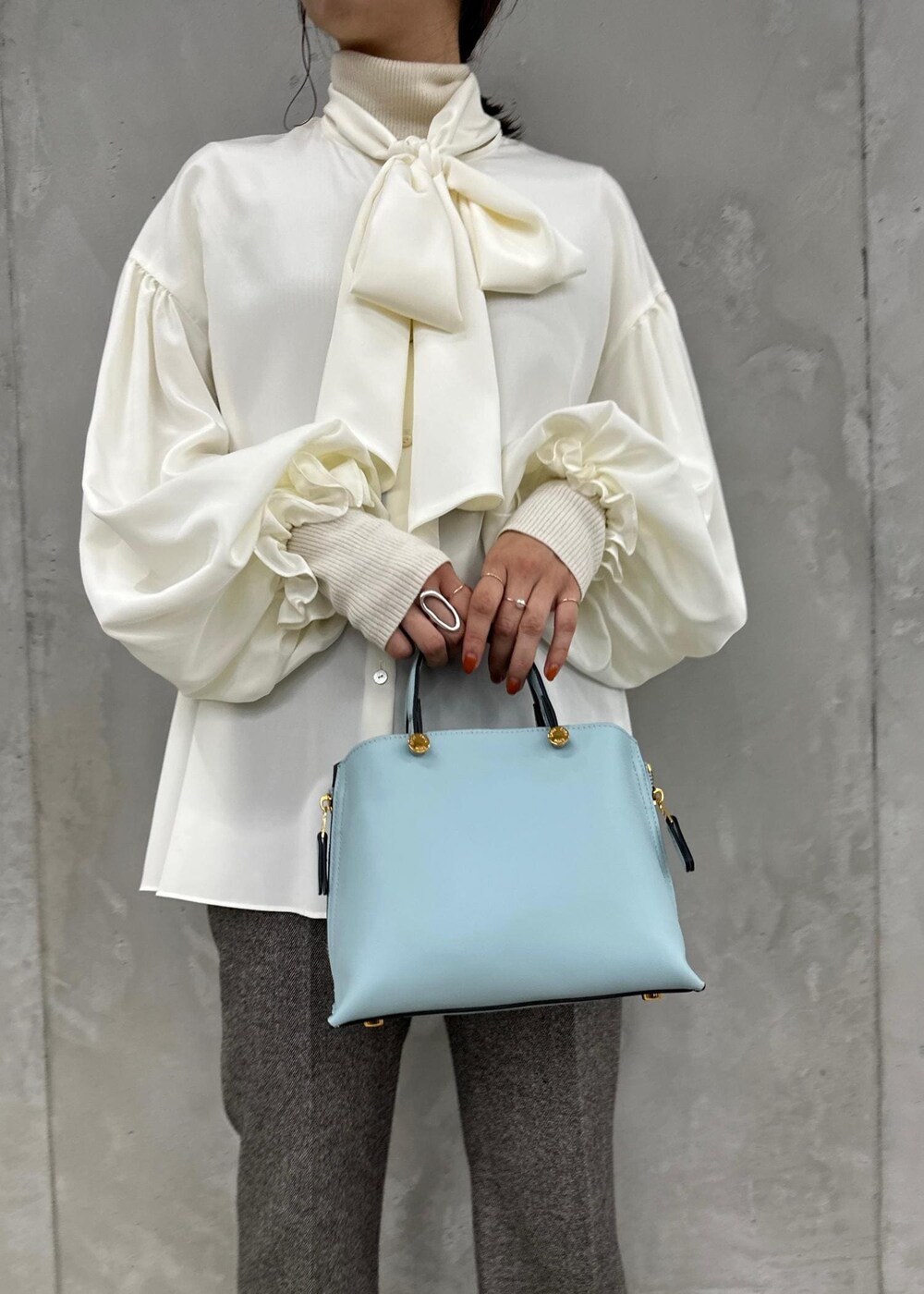 ブルー系のハンドバッグ、ベージュ系のパンプス、グレー系のその他パンツを着用したレディースの秋コーディネートの5枚目の写真