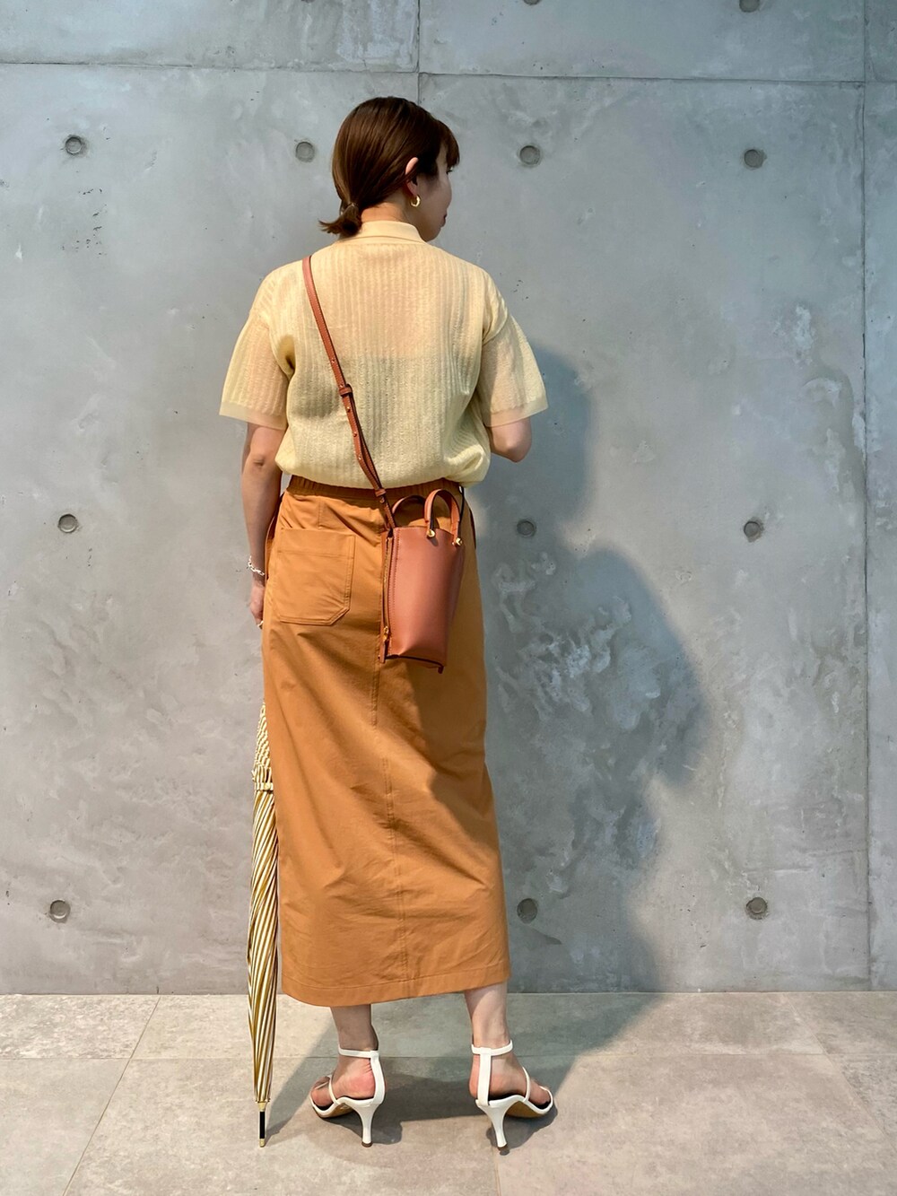 ベージュ系のニット/セーター、オレンジ系のスカート、ブラウン系のショルダーバッグを着用したレディースの春コーディネートの3枚目の写真