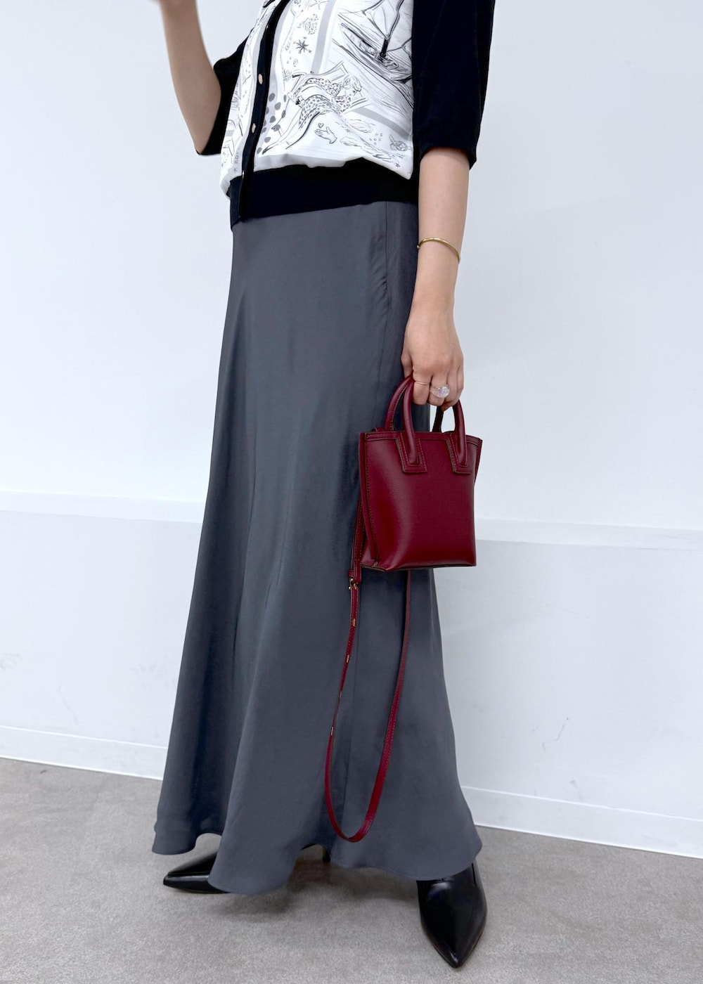 グレー系のスカート、ブラック系のシャツ/ブラウス、レッド系のショルダーバッグを着用したレディースの夏コーディネートの7枚目の写真