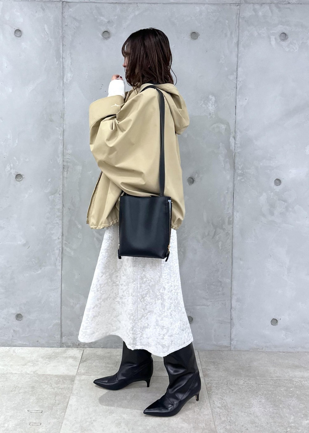 ブラック系のブーツ、ホワイト系のワンピース、ベージュ系のマウンテンパーカーを着用したレディースの秋コーディネートの3枚目の写真