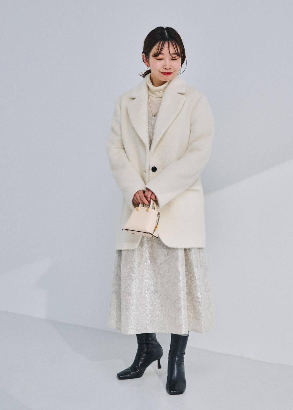 ベージュ系のショルダーバッグ、ブラック系のブーツ、ホワイト系のテーラードジャケットを着用したレディースの冬コーディネートの2枚目の写真