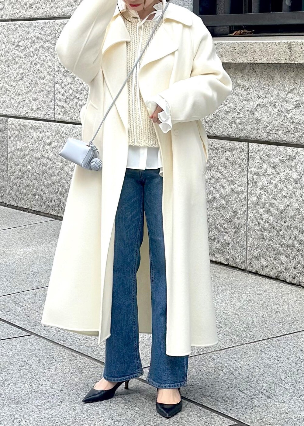 ブルー系のショルダーバッグ、ホワイト系のチェスターコート、ホワイト系のニット/セーターを着用したレディースの冬コーディネートの6枚目の写真