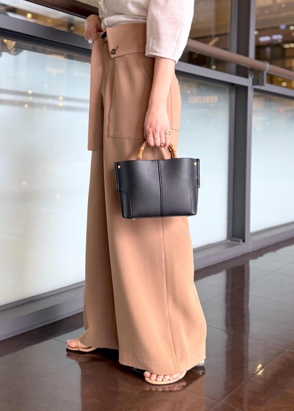 ブラック系のハンドバッグ、ベージュ系のシャツ/ブラウス、ブラウン系のその他パンツを着用したレディースの春コーディネートの6枚目の写真