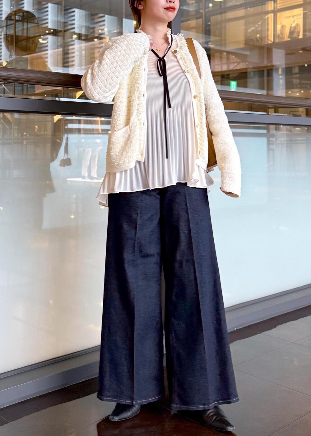 ブルー系のデニムパンツ、イエロー系のハンドバッグ、ホワイト系のノーカラージャケットを着用したレディースの秋コーディネートの8枚目の写真