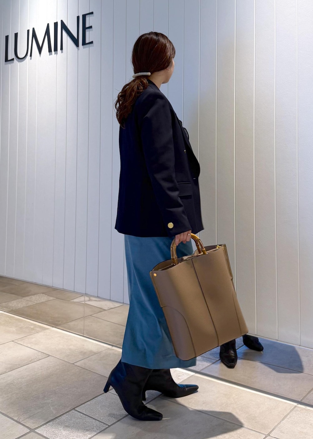 ベージュ系のトートバッグ、ブルー系のスカート、ブルー系のテーラードジャケットを着用したレディースの秋コーディネートの2枚目の写真