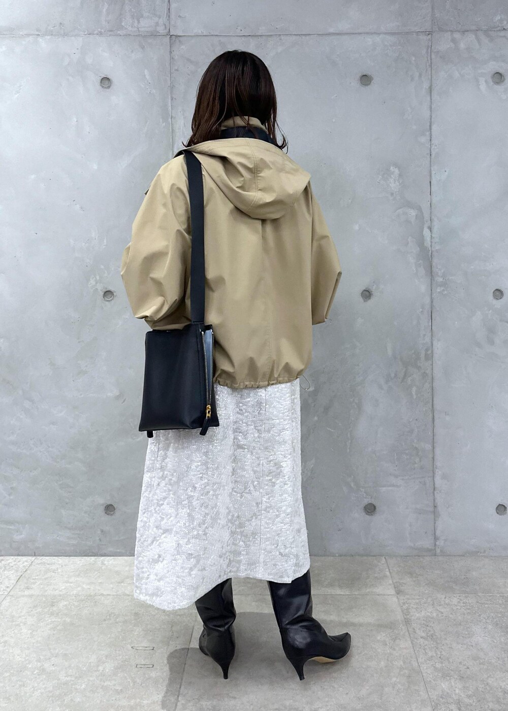 ブラック系のブーツ、ホワイト系のワンピース、ベージュ系のマウンテンパーカーを着用したレディースの秋コーディネートの4枚目の写真