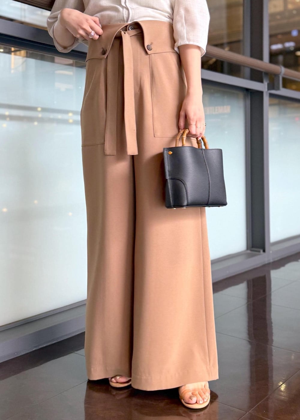 ブラック系のハンドバッグ、ベージュ系のシャツ/ブラウス、ブラウン系のその他パンツを着用したレディースの春コーディネートの5枚目の写真