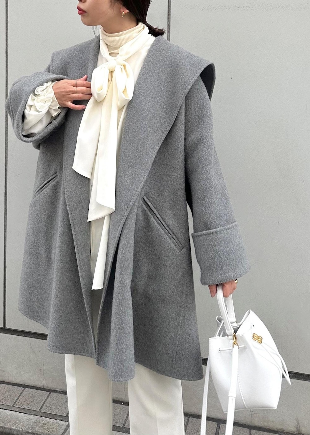 グレー系のその他アウター、ベージュ系のパンプス、ホワイト系のハンドバッグを着用したレディースの冬コーディネートの7枚目の写真