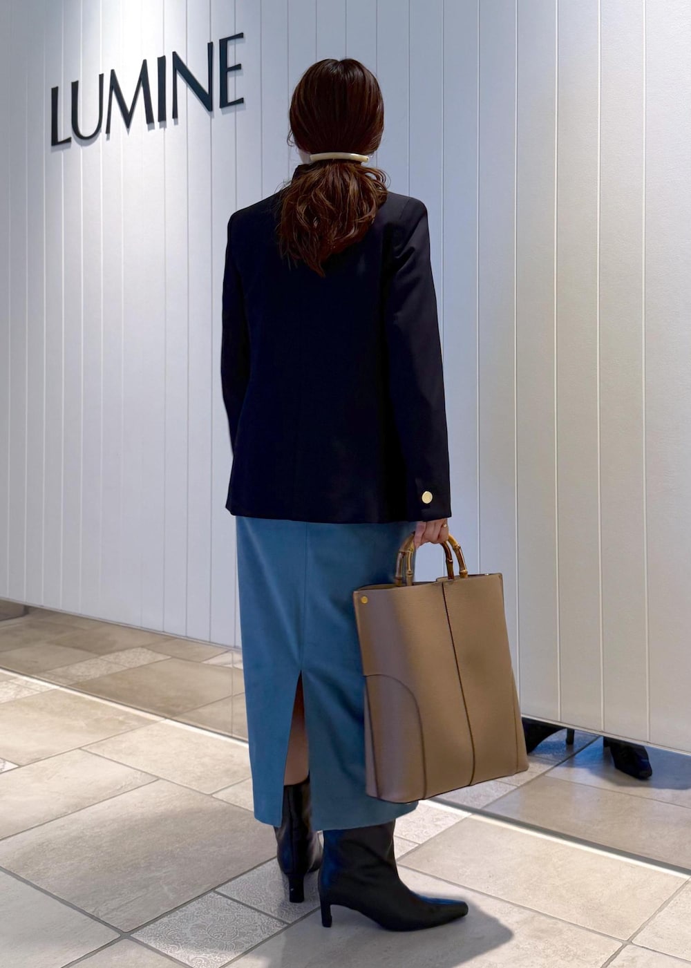 ベージュ系のトートバッグ、ブルー系のスカート、ブルー系のテーラードジャケットを着用したレディースの秋コーディネートの3枚目の写真