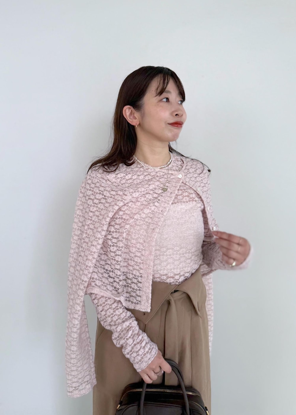 ブラウン系のハンドバッグ、ブラウン系のその他パンツ、ピンク系のカーディガン/ボレロを着用したレディースの夏コーディネートの5枚目の写真
