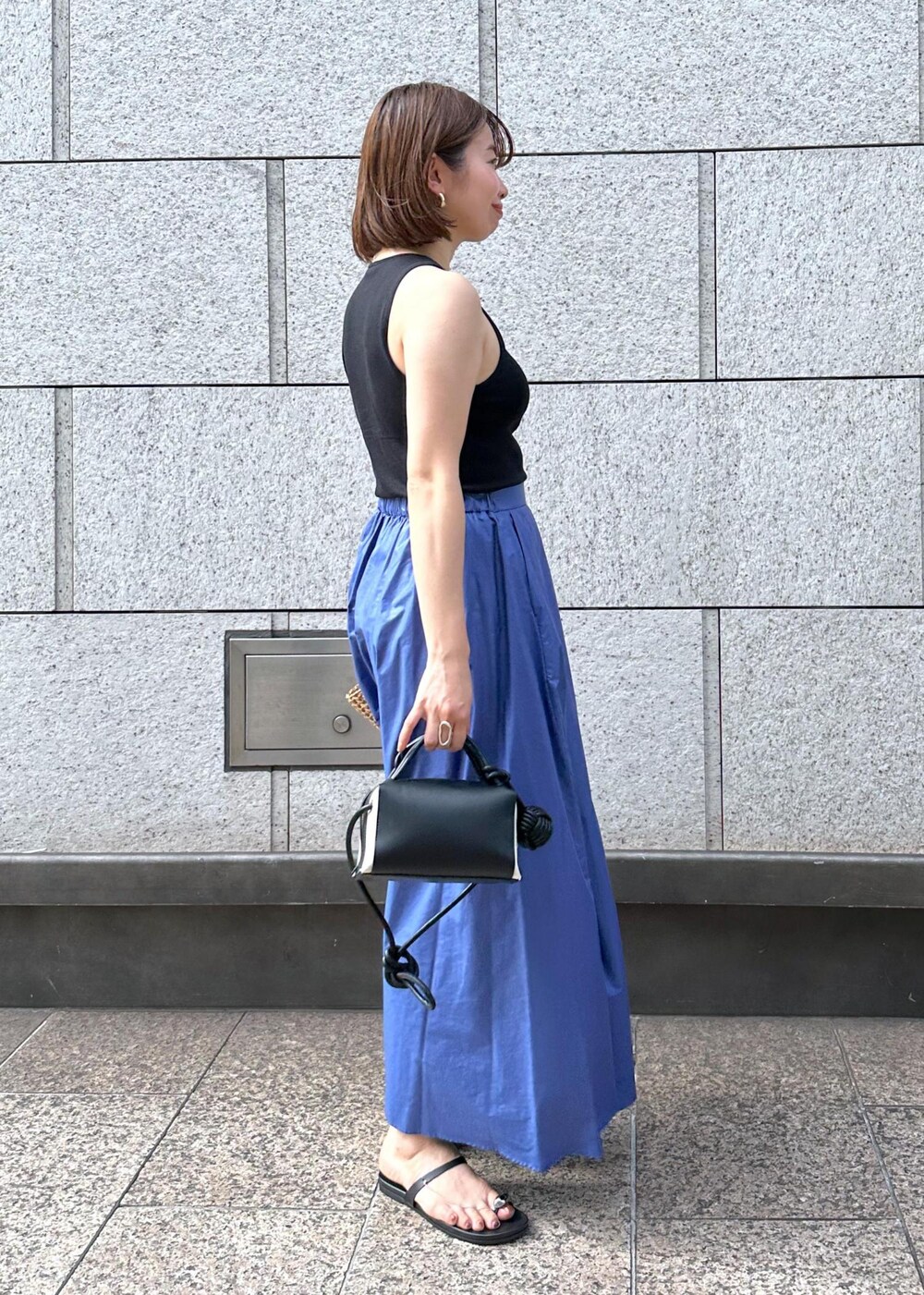 ブラック系のサンダル、ブルー系のスカート、ブラック系のタンクトップを着用したレディースの夏コーディネートの4枚目の写真