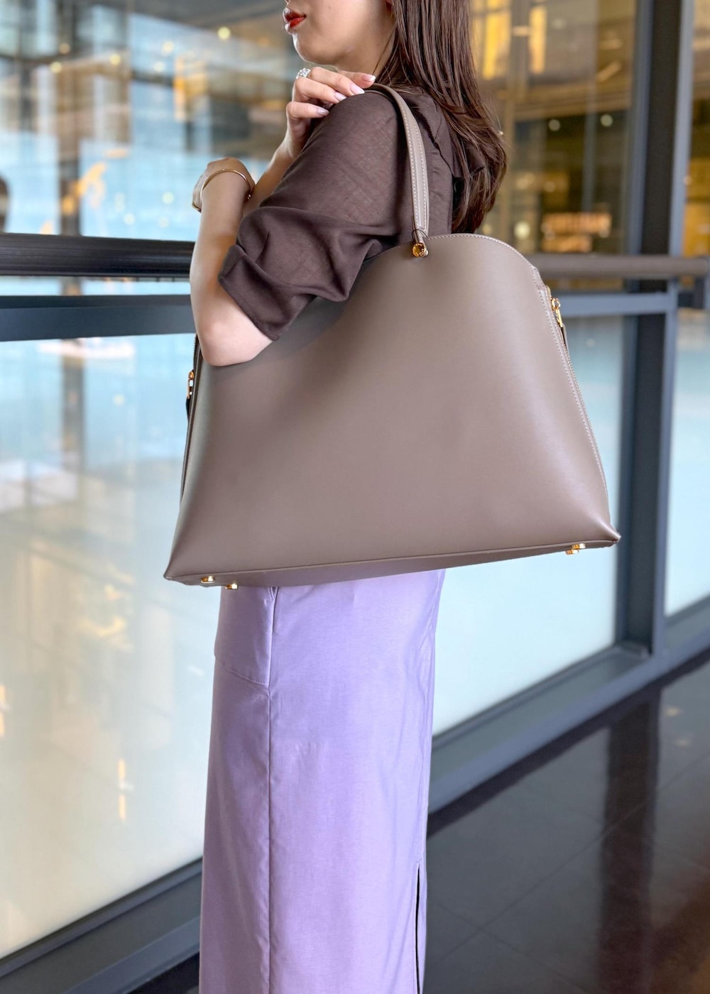 ブラウン系のトートバッグ、パープル系のスカート、ブラウン系のシャツ/ブラウスを着用したレディースの春コーディネートの6枚目の写真