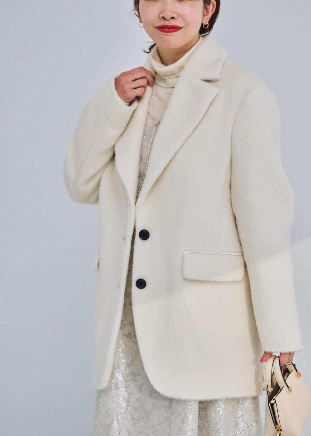 ベージュ系のショルダーバッグ、ブラック系のブーツ、ホワイト系のテーラードジャケットを着用したレディースの冬コーディネートの4枚目の写真