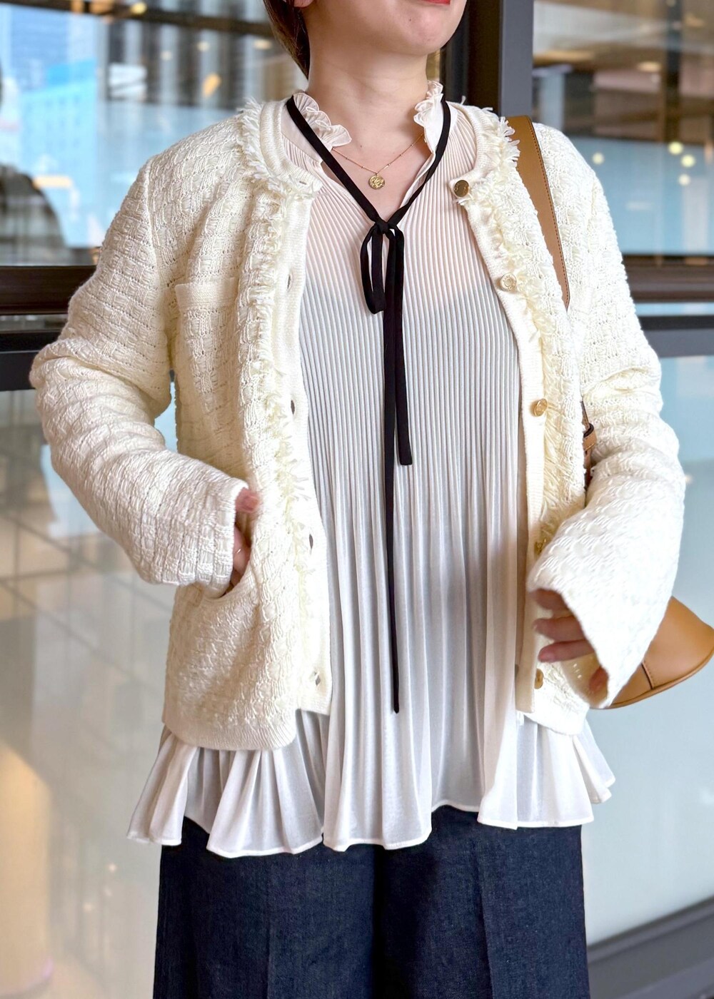 ブルー系のデニムパンツ、イエロー系のハンドバッグ、ホワイト系のノーカラージャケットを着用したレディースの秋コーディネートの5枚目の写真