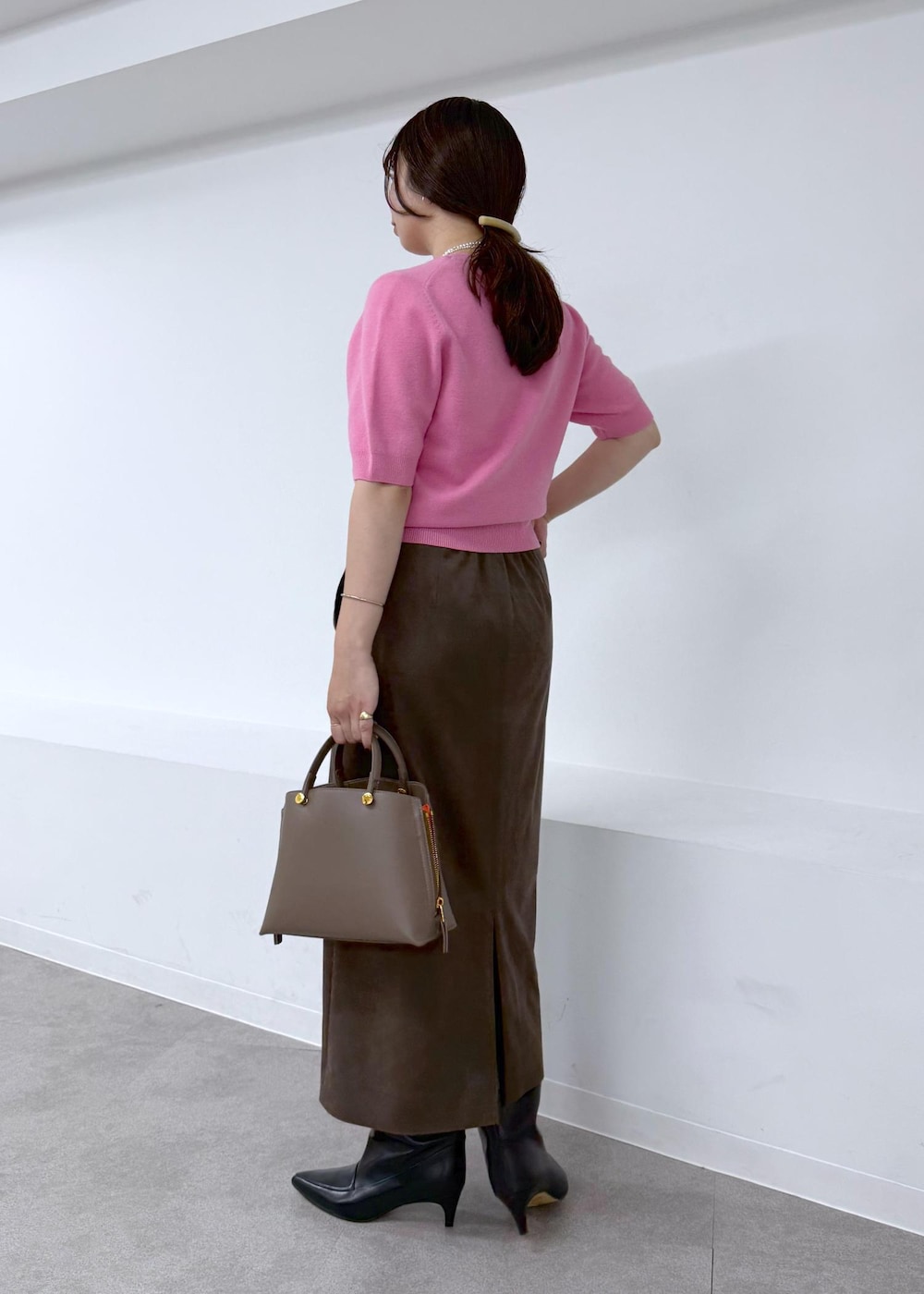 ブラック系のブーツ、ブラウン系のスカート、ブラウン系のハンドバッグを着用したレディースの秋コーディネートの2枚目の写真