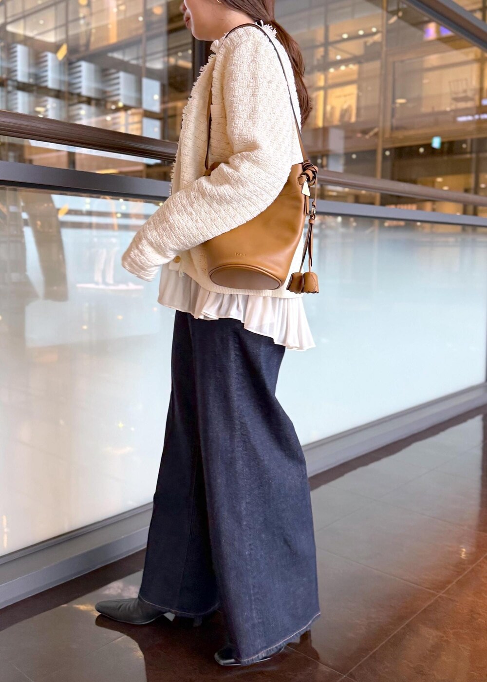 ブルー系のデニムパンツ、イエロー系のハンドバッグ、ホワイト系のノーカラージャケットを着用したレディースの秋コーディネートの7枚目の写真