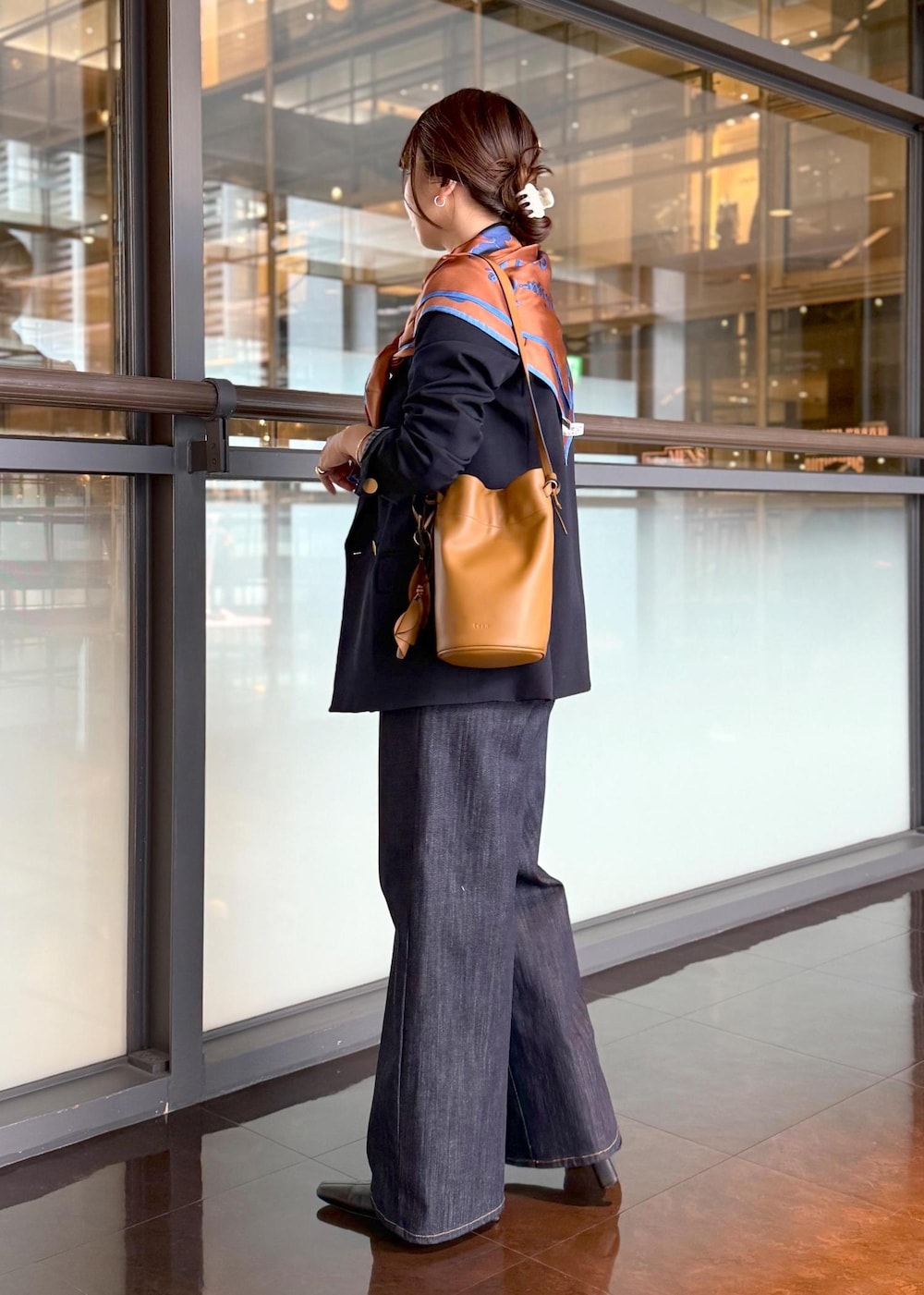 イエロー系のハンドバッグ、ブルー系のデニムパンツ、ホワイト系のカーディガン/ボレロを着用したレディースの秋コーディネートの2枚目の写真