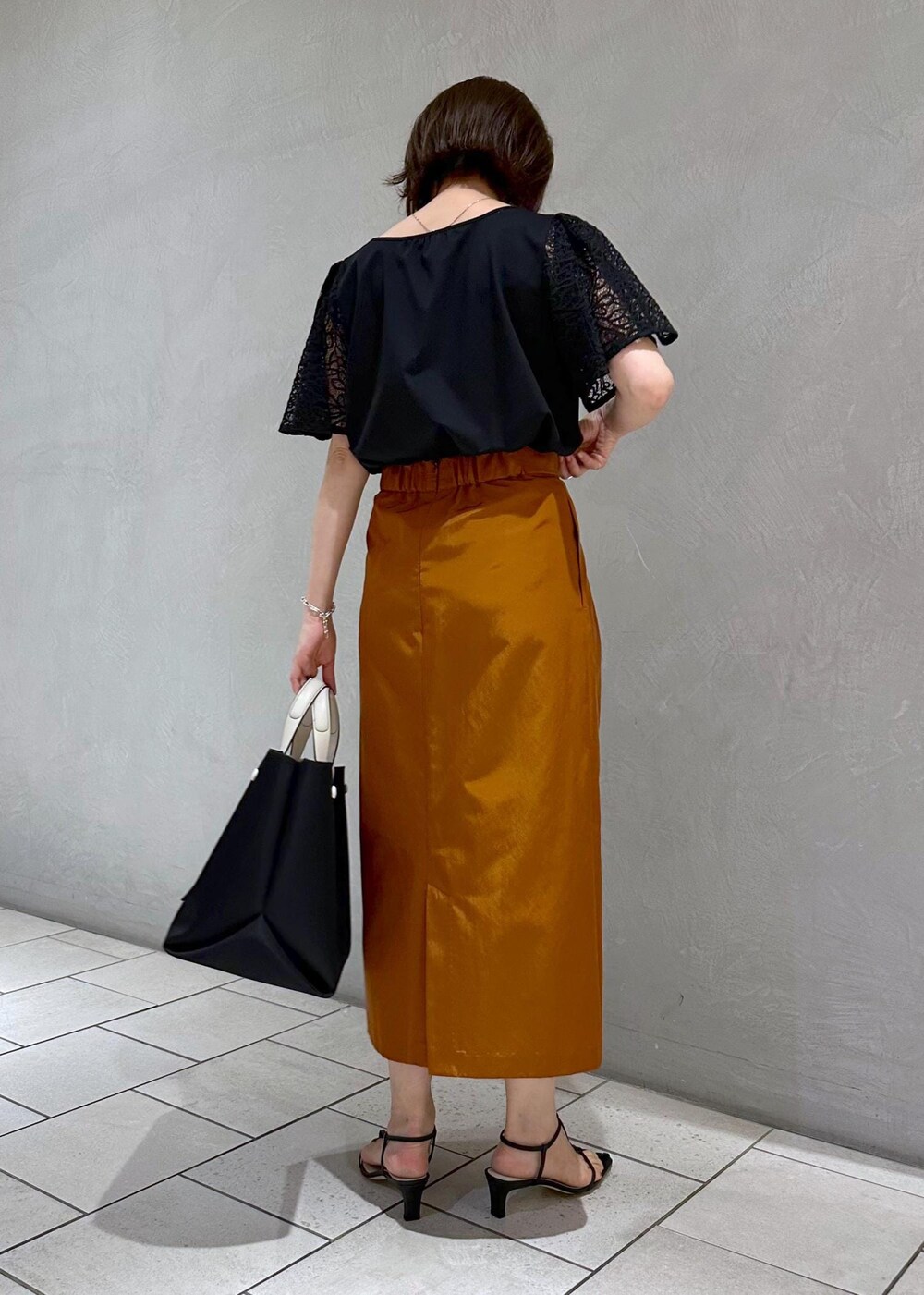 ブラック系のハンドバッグ、ブラック系のサンダル、ブラック系のTシャツ/カットソーを着用したレディースの夏コーディネートの3枚目の写真