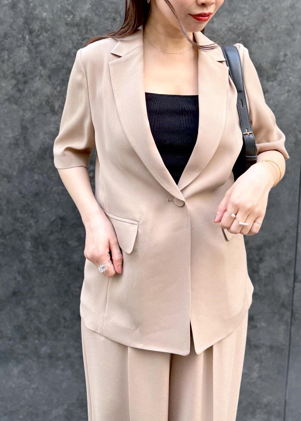 ベージュ系のその他パンツ、ベージュ系のテーラードジャケット、ブラック系のハンドバッグを着用したレディースの夏コーディネートの4枚目の写真