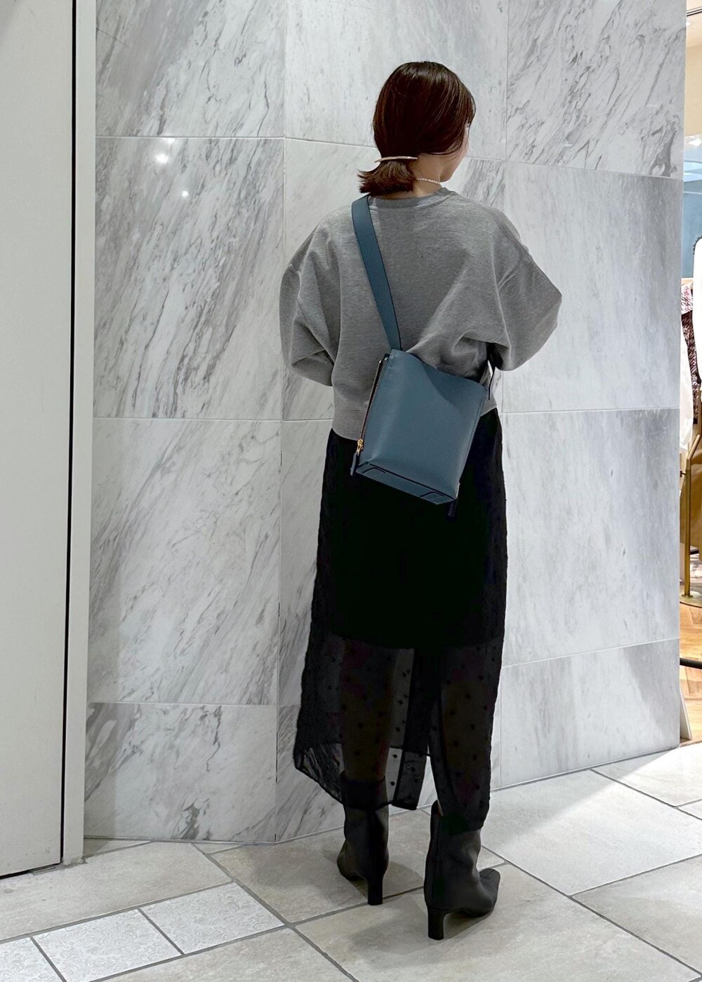 グレー系のスウェット、ブルー系のショルダーバッグ、ブラック系のスカートを着用したレディースの秋コーディネートの4枚目の写真
