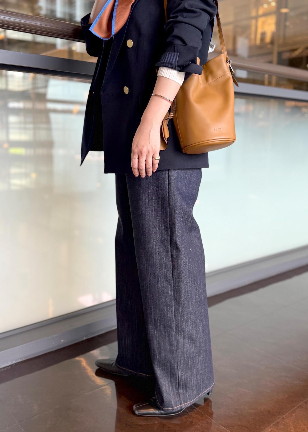 イエロー系のハンドバッグ、ブルー系のデニムパンツ、ホワイト系のカーディガン/ボレロを着用したレディースの秋コーディネートの6枚目の写真