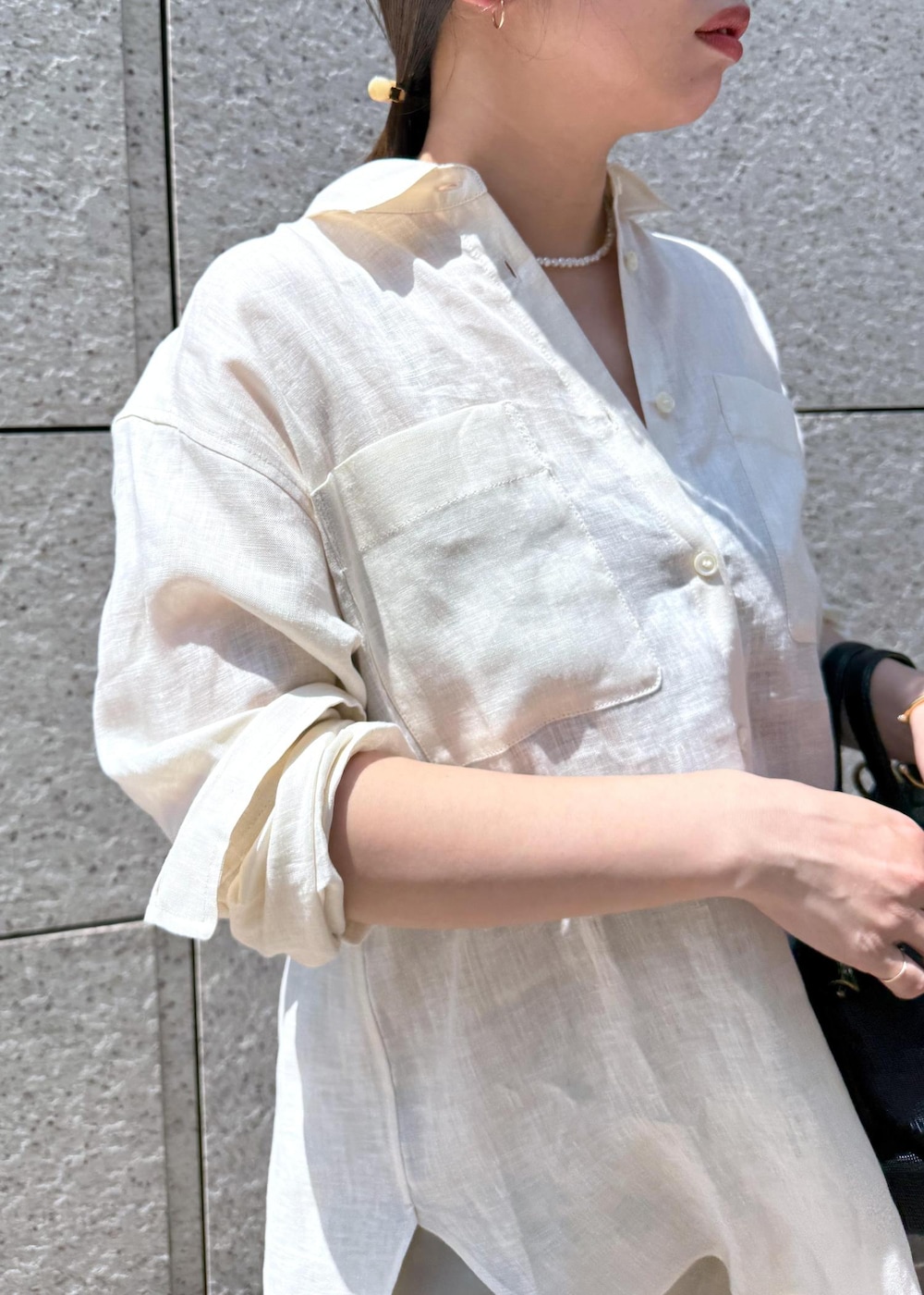 ブラック系のハンドバッグ、ベージュ系のスカート、ホワイト系のシャツ/ブラウスを着用したレディースの夏コーディネートの4枚目の写真