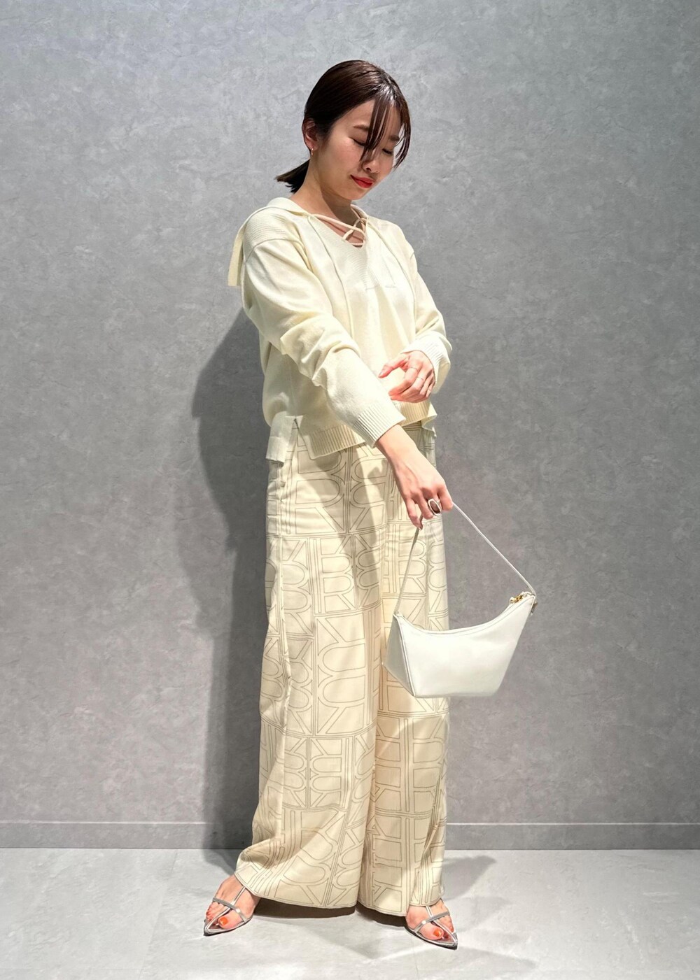 ホワイト系のニット/セーター、ホワイト系のその他パンツ、ホワイト系のハンドバッグを着用したレディースの春コーディネートの9枚目の写真