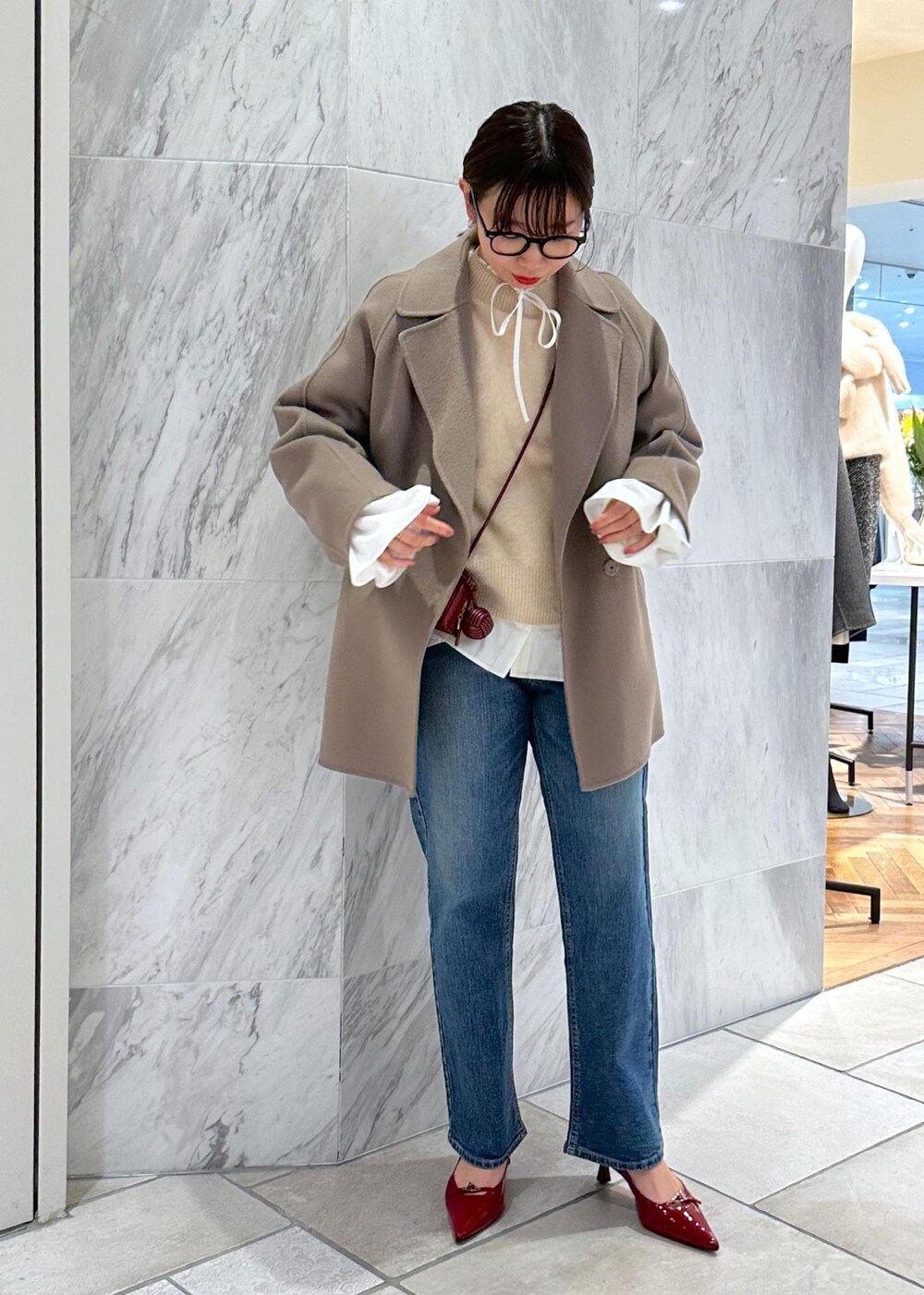 レッド系のパンプス、ベージュ系のニット/セーター、ベージュ系のピーコートを着用したレディースの冬コーディネートの8枚目の写真